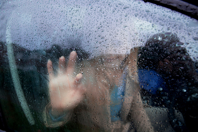 woman looking outside car window while it rains